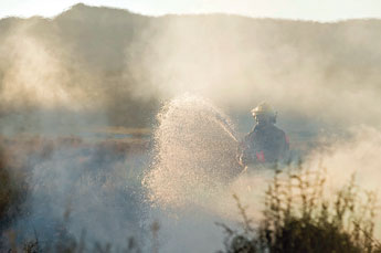 Navajo Estates volunteer firefighter Herb Bitsilly hoses down a large trash fire near Tohatchi April, 22. &copy; 2011 Gallup Independent / Cable Hoover 